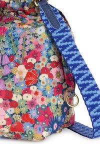 Schoudertas van stof met bloemenpatroon, voorzien van een blauwe geweven schouderband, gouden hardware en een afgeronde vorm met een zachte textuur.