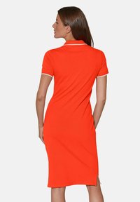 Oranges Polo-Kleid mit kurzen Ärmeln und slim fit. Kontrastierende weiße Akzente am Kragen und an den Ärmelsäumen. Seitliche Schlitzdetails am Saum.