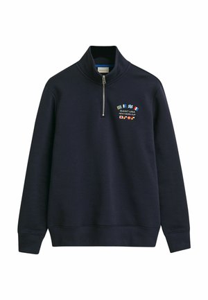 Námořnická modrá mikina s vysokým límcem a polo zipem. Na hrudi má vyšívané vlajky a text "GANT USA NEW HAVEN CUP".