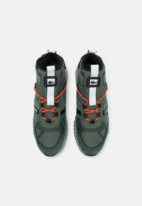 Zielone syntetyczne sneakersy o wysokim kroju, z pomarańczowymi sznurówkami, białymi akcentami i teksturowaną podeszwą. Czarne wykończenie dopełnia całość.