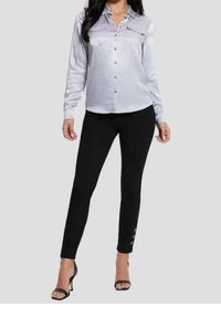 Silver satin long-sleeve button-up shirt with two chest pockets, paired with black ankle-length pants featuring button accents on cuffs.