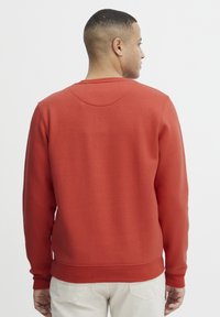 Rode sweatshirt met een ronde halslijn en geribde voeringen. Gemaakt van een zacht materiaal. Heeft een effen achterkant zonder zichtbare logo's.
