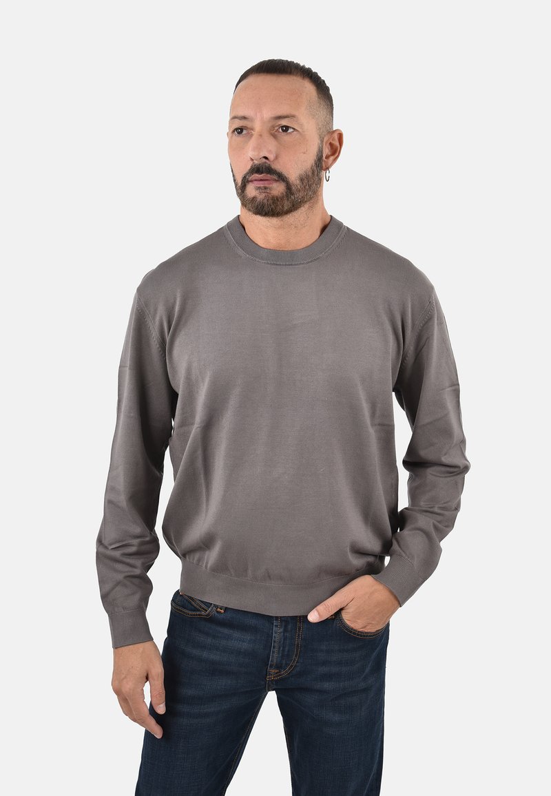 Jersey de punto gris con cuello redondo y mangas largas, que presenta una textura suave y un dobladillo acanalado, combinado con unos vaqueros de mezclilla azul oscuro.
