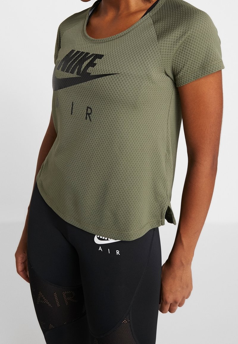 Camiseta de malla Nike en verde oliva, de manga corta y cuello redondo, con un estampado de logo negro y aberturas en los lados del dobladillo.