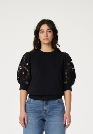 Schwarzer Pullover mit aufgesetzten Ballonärmeln und Cut-out-Designs. Das Textil wirkt weich; gerippte Bündchen an Ärmelenden und Saum. Lässige Passform.