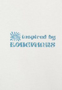 Bílá látka s modrým textem "inspirováno BOHEMANY." Na levé straně se nachází stylizovaná modrá sluneční grafika. Jemná textura, neformální písmo.