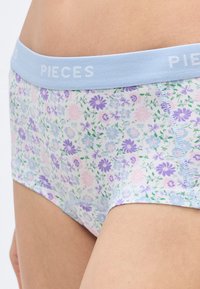 Bombažno spodnje perilo z rožnatim vzorcem v pastelnih barvah, z vijoličnimi in roza cvetovi ter svetlo modrim pasom z napisom "PIECES".
