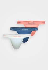 Tričko tri páry tang Calvin Klein v koralovej, námorníckej a svetlozelenej farbe. Každé z nich má mäkkú tkaninu, elastický pás a logom. 