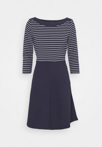 Marinblå klänning med vita horisontella ränder, med rundad halsringning, trekvartsärmar och en texturerad kjol med en sidoklyvning.