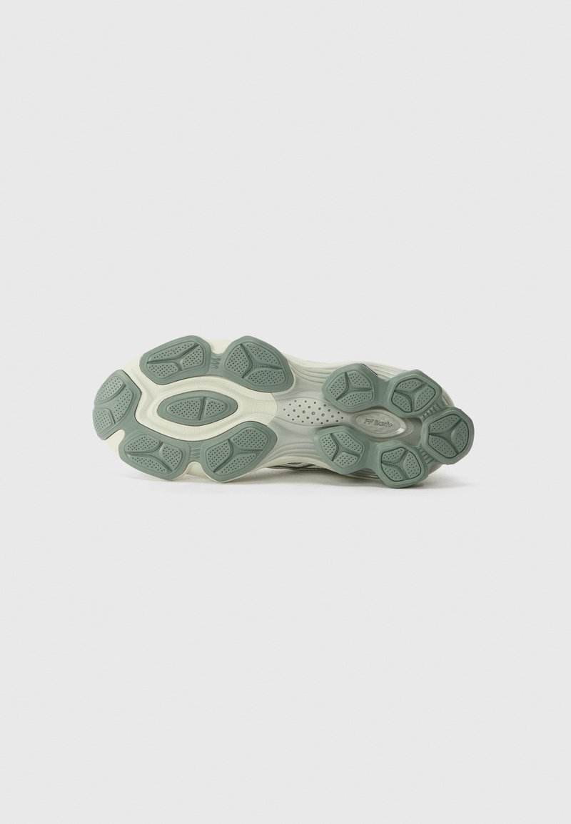 Semelle de sneaker dans un mélange de crème et de vert doux. Présente un caoutchouc texturé avec des motifs uniques pour une adhérence et une flexibilité accrues.