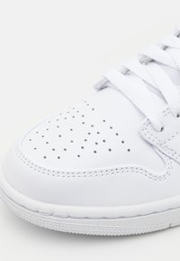 Witte lederen sneaker met geperforeerde teendetail, platte veters en een gestructureerde rubberen zool. Geborduurde accenten langs de randen.