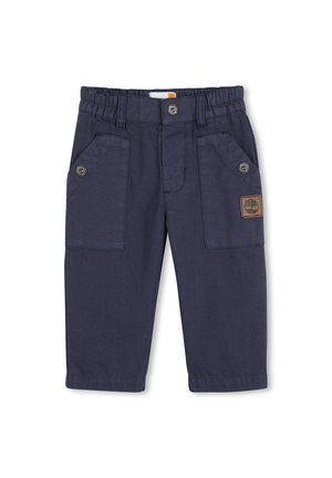 Marineblaue Baumwollhose mit elastischem Bund, zwei Seitentaschen, Knopfdetails und einem kleinen braunen Logopatch.