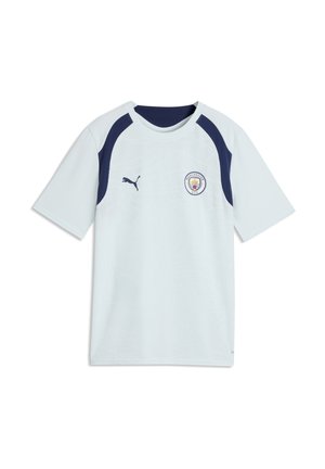 Jasnoniebieska koszulka piłkarska Manchester City z ciemnoniebieskimi panelami na ramionach, logo Puma na prawej stronie klatki piersiowej i herbem klubu na lewej stronie klatki piersiowej.