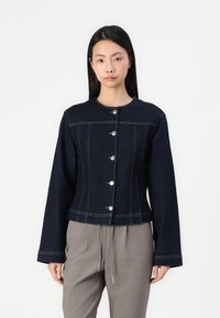 Mörk denimjacka med rund hals, långa ärmar, sex silverknappar fram och kontrasterande sömnadsdetaljer.