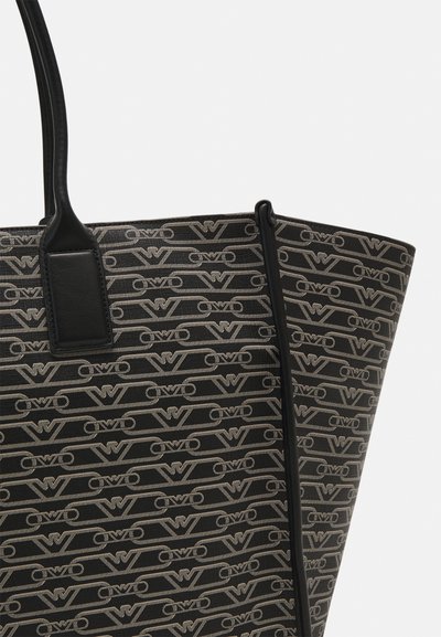Borsa a tote nera in materiale canvas con un motivo a logo ripetuto in beige. Texture liscia, manici robusti, forma rettangolare.