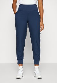 Mörkblå joggingbyxor med hög midja, två sidofickor och ribbade muddar. Tillverkade av ett mjukt, stretchigt material för komfort.