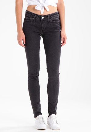 Jeans ajustados de color gris oscuro, fabricados con una mezcla de algodón y denim. Cuentan con cinco bolsillos, pasadores para cinturón y un cierre de cremallera con botón. Textura suave.