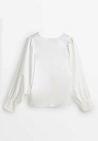 Blouse blanche à finition satinée lisse, avec des manches longues bouffantes, un col rond et un détail simple de couture dans le dos.