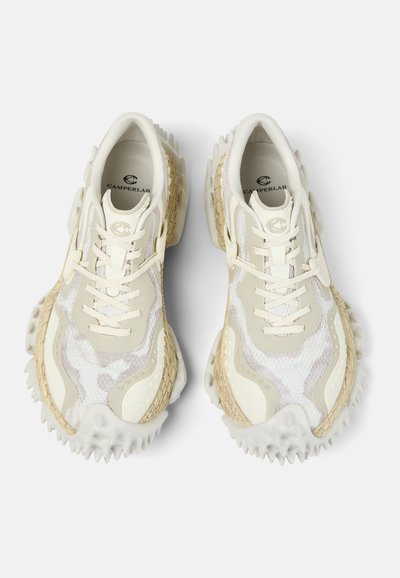 Pár béžových a bílých tenisek CamperLab s texturovanými podrážkami a síťovanými detaily, pohled zhora na bílém pozadí.