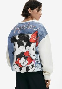 Felpa oversize in denim e bianco con una stampa a cartone animato di Topolino e Minnie, con "Insieme" ricamato in corsivo rosso sul retro.