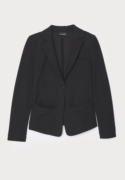 Fekete zakó textúrált anyagból, egy gombbal záródik, cakkos hajtókával és két elülső zsebbel rendelkezik.