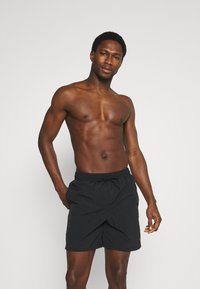 Pantaloni da bagno neri con vita elasticizzata e cordoncino. Tessuto leggero con una texture liscia. Nessun motivo visibile o dettagli in metallo.