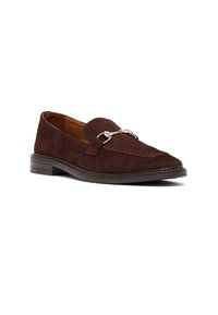 Mocassino in suede marrone scuro da uomo con tacco basso e dettagli in metallo a forma di morsetto argentato sul davanti, angolato per mostrare il lato esterno e la parte anteriore.