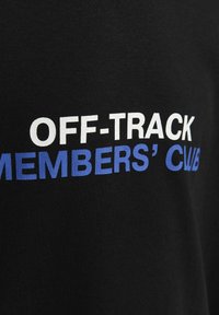 Camiseta de algodón negra con texto en color blanco y azul en negrita que dice "MEMBRES DEL OFF-TRACK CWB" en la parte frontal. Textura suave.