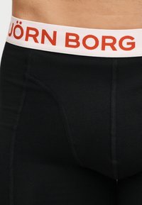 Μαύρο μπόξερ με ορατές ραφές και λευκή μέση με κόκκινο κείμενο "BJÖRN BORG" σε γυμνή μέση.