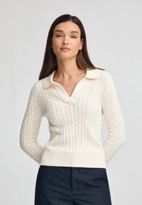 Elfenbeinfarbener Pullover mit Kabelstrickmuster, V-Ausschnitt und Kragendesign. Besitzt gerippte Bündchen und Saum, die eine strukturierte Optik bieten.