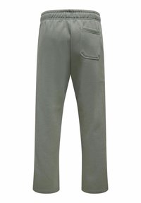 Joggers en coton vert avec une coupe décontractée, une taille élastique et une poche arrière unique. Le tissu semble doux et a une texture lisse.
