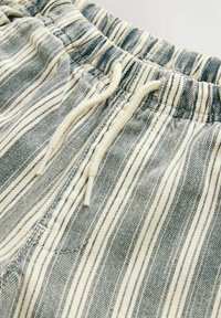 Shorts rayés avec une taille élastique, teintes bleues et blanches, en tissu de coton, dotés d'un cordon de serrage et de poches latérales.