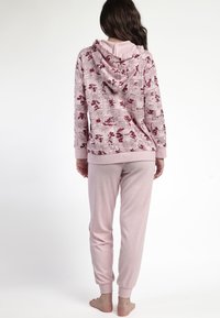 Sudadera con capucha rosa con estampado de cómic, combinada con pantalones de chándal ligeros a juego. Tela suave, corte relajado y puños en los pantalones.