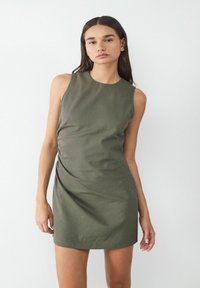 Knielange, mouwloze jurk in olijfgroen met een gestructureerd streeppatroon en een geplooid detail aan één kant. Glad stoffen afwerking.