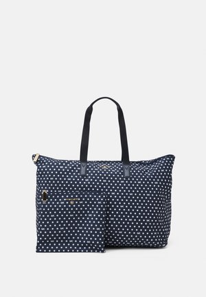 Granatowa torba na ramię i dopasowany woreczek w białe grochy z wzorem logo "MK", z czarnymi uchwytami i złotymi elementami zamka.