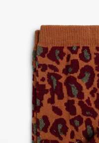 Calcetines con estampado de leopardo en naranja, con acentos en burdeos y verde. Textura de punto con puño acanalado. Patrón animal distintivo en toda la superficie.
