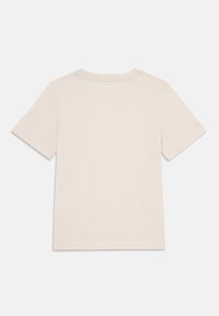 Tricou din bumbac de culoare bej deschis, cu mâneci scurte, guler rotund și un design simplu, având o textură netedă și fără modele sau accente vizibile.