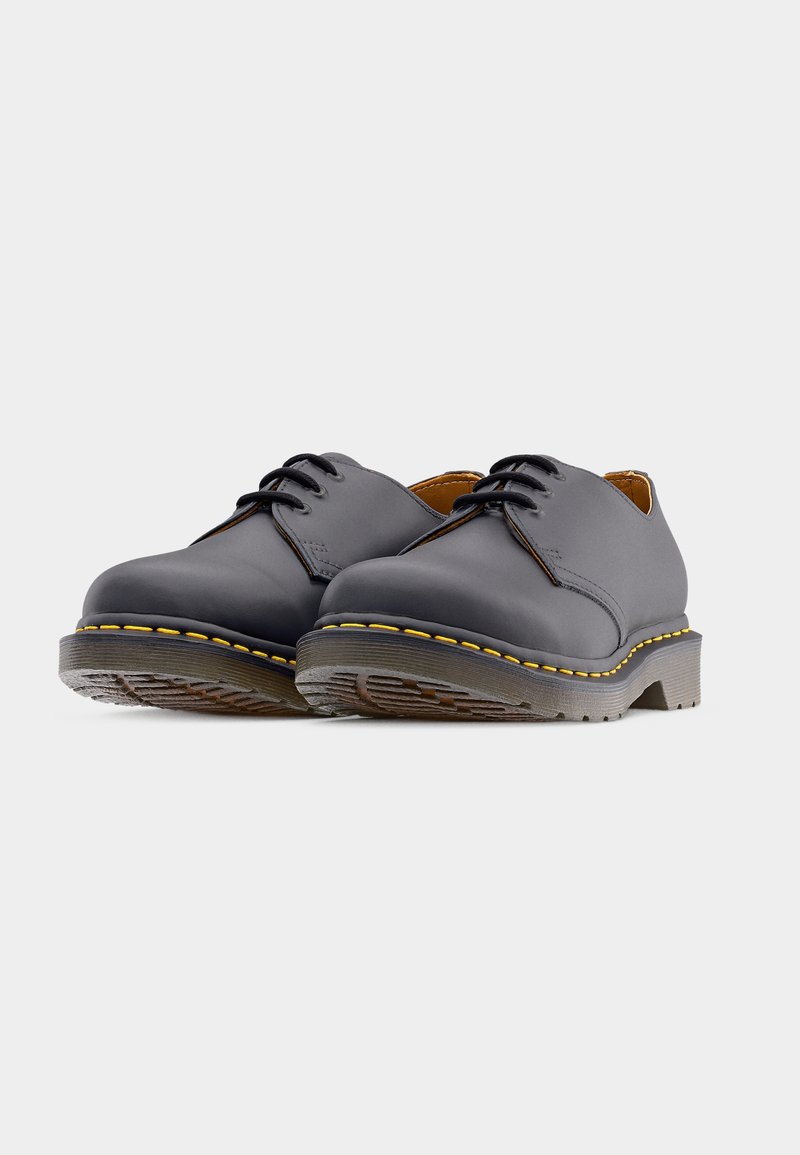 Scarpe di pelle grigia con punta arrotondata, dotate di lacci neri, cuciture gialle a contrasto e suola in gomma texturizzata.