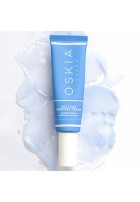 Oskia Rest Day Comfort Cream in einer hellblauen Tube mit weißen Akzenten, ausgestattet mit einem strukturierten Deckel und Cremes darum herum.