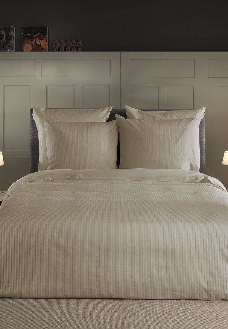 Beige gestreiftes Bettwäsche-Set mit zwei passenden Kissenbezügen. Glatte Textur und einfaches Design, auf einem dunkelgrauen gepolsterten Bettgestell.