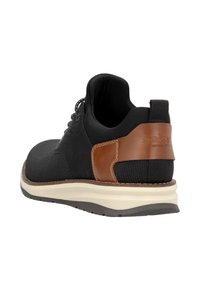 Baskets noires avec une surface texturée et un accent en cuir marron au talon. Comprend une semelle blanche et une semelle en caoutchouc grise pour l'adhérence.