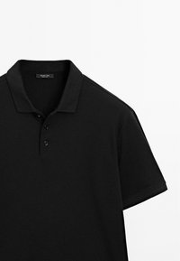 Sort polo skjorte lavet af blød bomuld, med en klassisk krave, tre knapper og korte ærmer med en glat overflade.