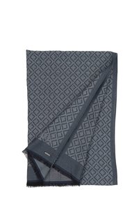 Manta tejida gris con un patrón geométrico de diamantes, con bordes con flecos y una textura suave. Pequeña etiqueta de la marca visible en uno de los bordes.