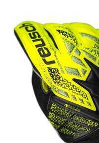 Helles gelbes Torwarthandschuh mit strukturierten schwarzen Akzenten und geometrischen Mustern, mit verstärkten Griffbereichen für verbesserte Leistung.