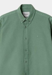 Camisa verde de botones, hecha de algodón, con un cuello clásico, botones en la parte frontal y un pequeño logo bordado en el pecho.