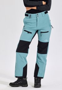 Light blue and black softshell pants with multiple zippered pockets, a sleek fit, and reinforced knees. Features logo on the left thigh.