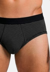 Zwart-wit gestreepte slip met een zwarte elastische tailleband. De stof lijkt zacht met een nauwsluitende pasvorm en zonder zichtbare naden.