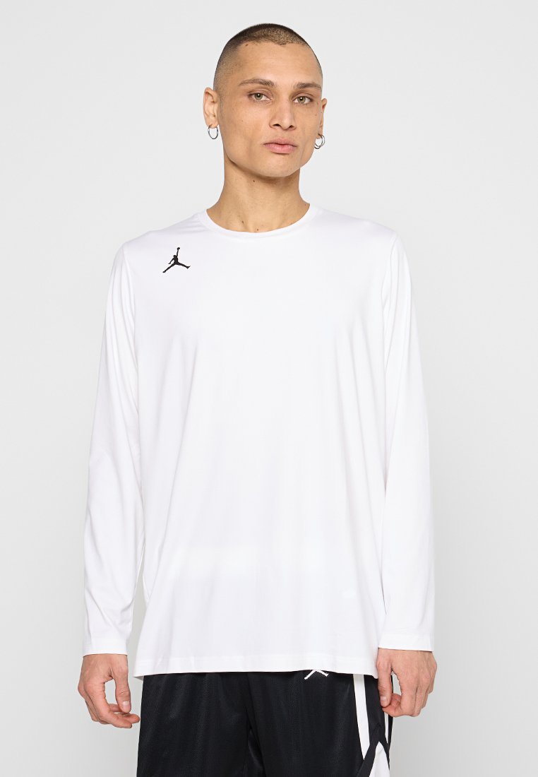 Chemise blanche à manches longues en tissu lisse, dotée d'un logo Jordan noir sur le côté gauche de la poitrine. Design simple avec un col rond.