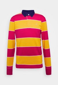 Långärmad pikétröja med rosa, gula och vita horisontella ränder. Mörkblå krage med knappdetalj. Tillverkad av bomull, avslappnad passform.