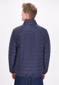 Marineblauer Puffer-Jacke mit vertikal gestepptem Design, hohem Kragen und elastischen Bündchen; leichtes Material mit glatter Textur.